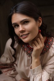 Photo of Beautiful woman wearing embroidered dress and ornate beaded necklace outdoors. Ukrainian national clothes
