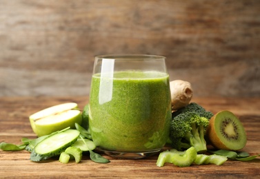 Green juice and fresh ingredients on wooden table