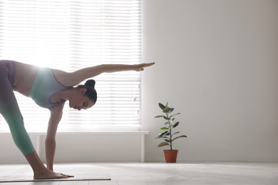 Young woman practicing extended triangle asana in yoga studio. Utthita Trikonasana pose