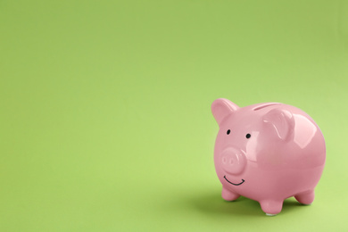Pink piggy bank on green background. Space for text