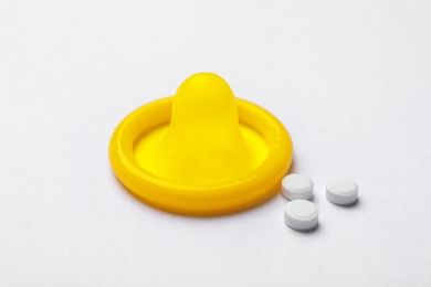 Yellow condom and birth control pills on white background. Safe sex concept