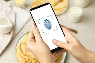 Woman scanning fingerprint on smartphone indoors, closeup. Digital identity