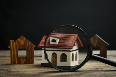 House models and magnifying glass on wooden table. Search concept