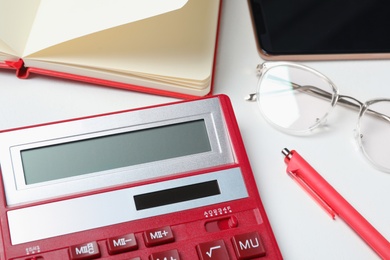 Calculator, glasses, smartphone and stationery on white table, closeup. Tax accounting