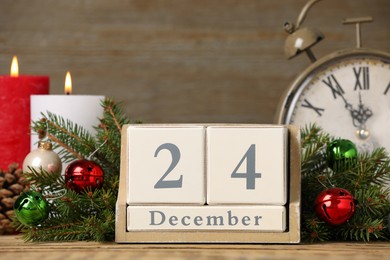 December 24 - Christmas Eve. Wooden block calendar, alarm clock and festive decor on table