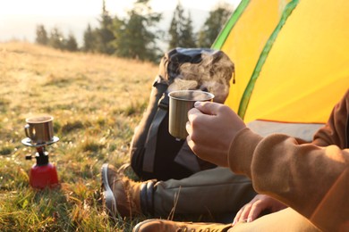 Man with cup of hot drink in camping tent, closeup