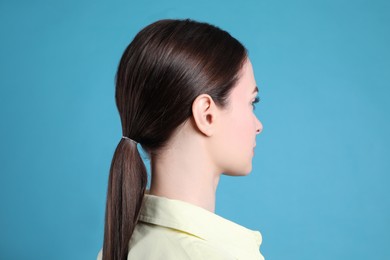 Side view of young woman on light blue background