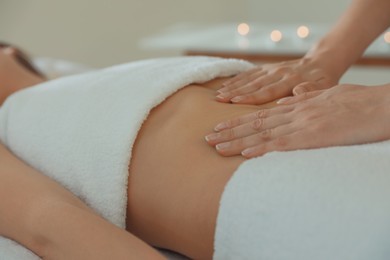 Woman receiving professional belly massage in wellness center, closeup