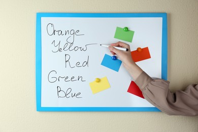 Woman matching colors on white board, closeup. ABA therapy concept