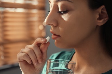 Young woman taking abortion pill indoors, closeup