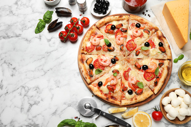 Tasty pizza with seafood and ingredients on white marble table, flat lay. Space for text