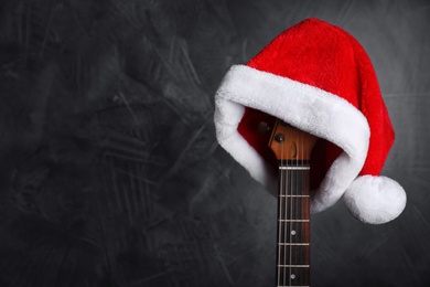 Guitar with Santa hat on black background, space for text. Christmas music