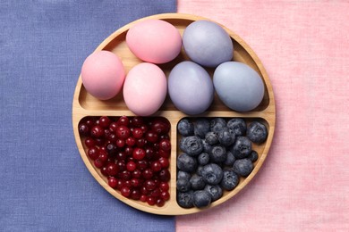 Photo of Painted Easter eggs with natural organic dyes (blueberries and cranberries) on color fabric, top view