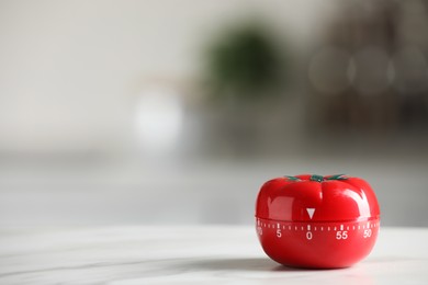 Kitchen timer in shape of tomato on white table against blurred background. Space for text