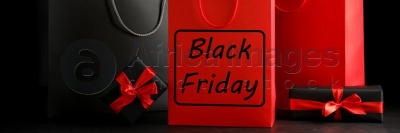 Paper shopping bags and gift boxes on dark background, banner design. Black Friday sale