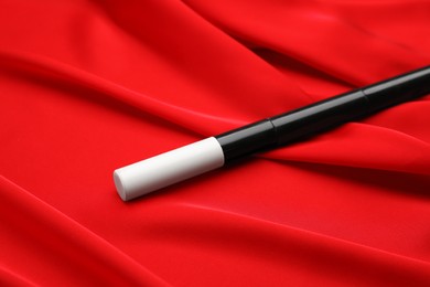Beautiful black magic wand on red fabric, closeup