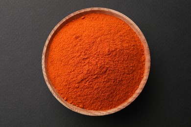 Photo of Wooden bowl with paprika powder on grey background, top view