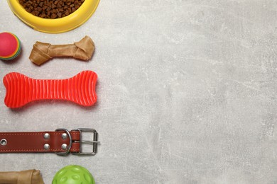 Flat lay composition with dog collar, toys and food on grey table. Space for text