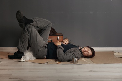 Poor homeless man sleeping on floor near dark wall