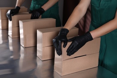 People packing cardboard boxes at production line, closeup