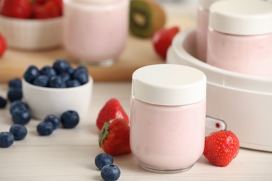 Portion jars for yogurt maker and different fruits on white wooden table, closeup