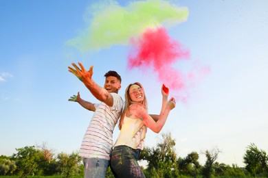 Photo of Happy couple with colorful powder dyes outdoors. Holi festival celebration