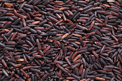 Uncooked organic brown rice as background, top view
