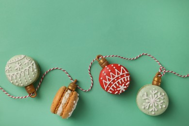 Beautifully decorated Christmas macarons with rope on turquoise background, flat lay. Space for text