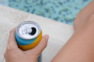 Photo of Woman holding aluminum can with beverage near swimming pool, closeup