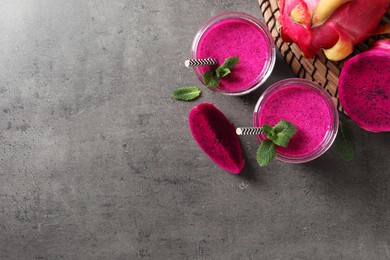Delicious pitahaya smoothie, fruits and fresh mint on grey table, flat lay. Space for text