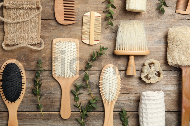 Flat lay composition with hair brushes and combs on wooden background