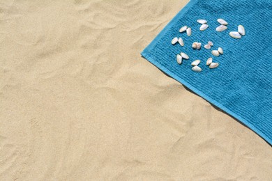 Photo of Towel and seashells on sand, above view with space for text. Beach accessory