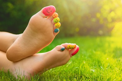 Teenage girl with smiling faces drawn on toes outdoors, closeup. Space for text