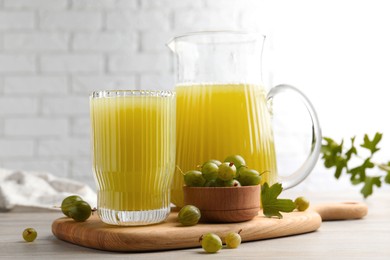 Photo of Tasty gooseberry juice and fresh berries on light wooden table