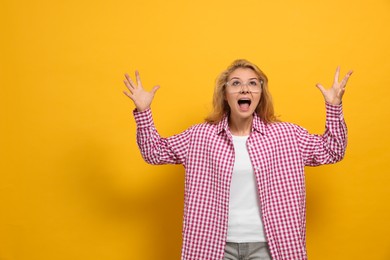 Photo of Aggressive young woman screaming with rage on yellow background. Space for text