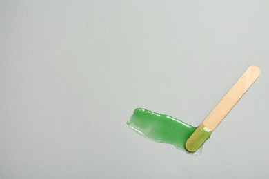 Spatula with wax on grey background, top view. Space for text