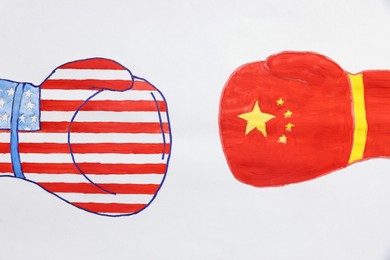 Boxing gloves with American and Chinese flags drawn on white paper, top view. Trade war