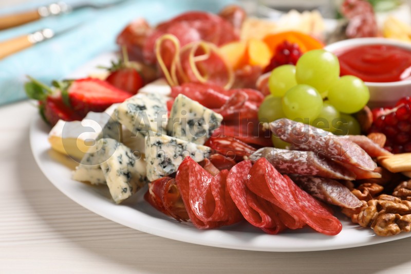 Plate of different appetizers with dip sauce on white table, closeup