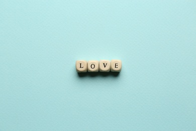 Mini cubes with letters forming word Love on light blue background, flat lay