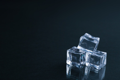 Crystal clear ice cubes on black background. Space for text