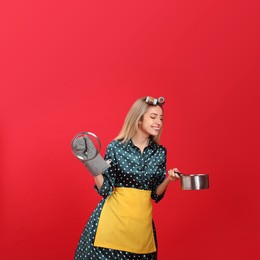 Young housewife with saucepan on red background