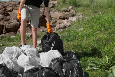 Man with trash bags full of garbage outdoors, closeup. Environmental Pollution concept