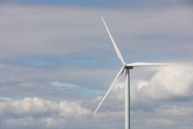 Photo of Wind turbine against cloudy sky. Alternative energy source