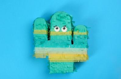 Bright cactus pinata on light blue background, top view