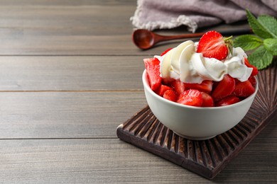 Delicious strawberries with whipped cream served on wooden table. Space for text