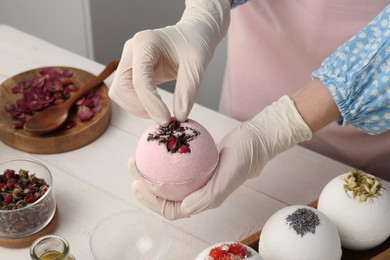 Woman in gloves making bath bomb at white table, closeup