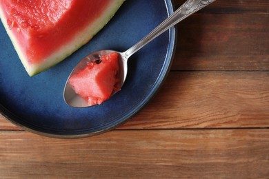 Sliced fresh juicy watermelon and spoon on wooden table, top view. Space for text