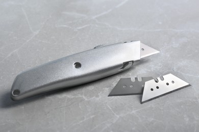 Utility knife and blades on light grey table, closeup