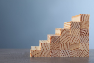 Steps made with wooden blocks on grey table, space for text. Career ladder