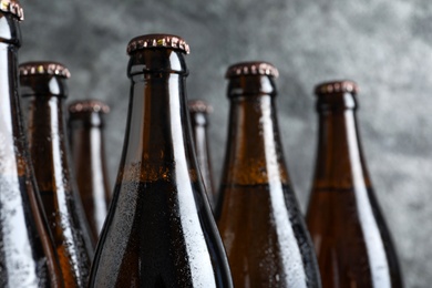 Photo of Bottles of beer on grey background, closeup. Space for text